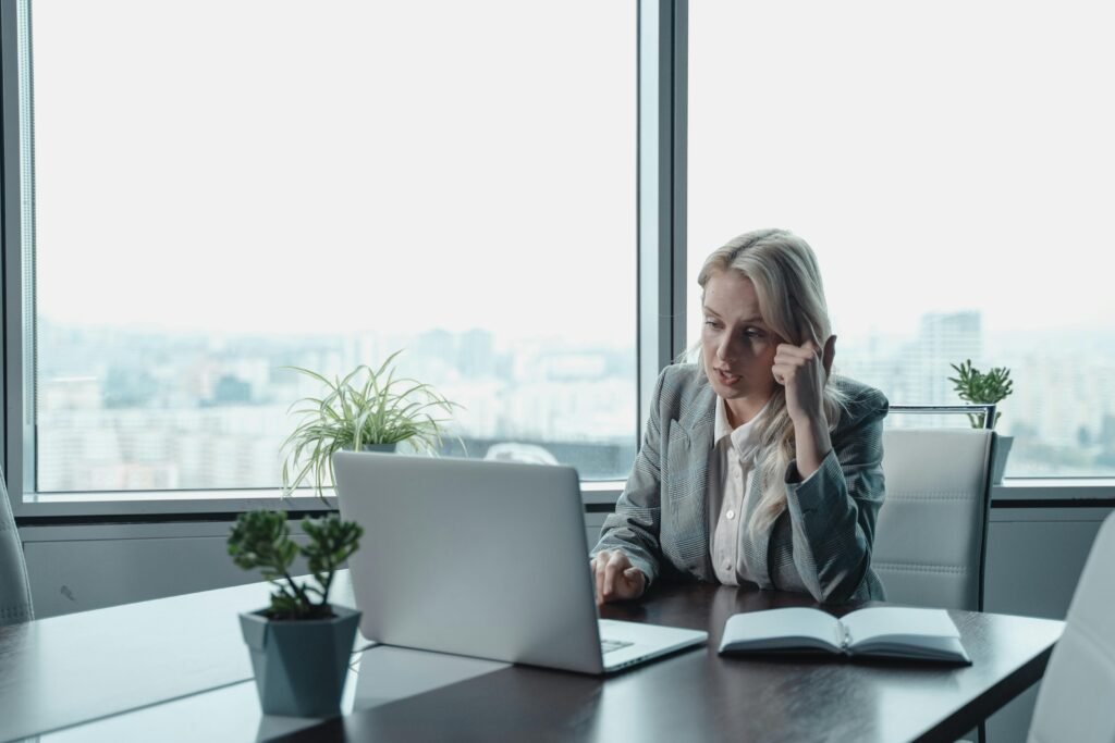 Professional woman engaged in a video meeting at a modern office desk with a laptop.