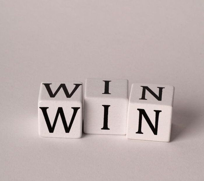 Three white dice spelling 'WIN' on a plain backdrop, symbolizing success and positivity.